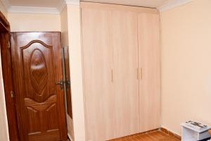 Zimmer mit einem Holzschrank und einer Tür in der Unterkunft The Hideout Thika Town in Thika