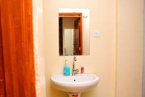 y baño con lavabo blanco y espejo. en The Hideout Thika Town, en Thika