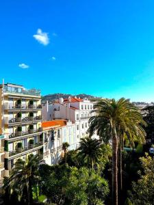 a large building with palm trees in front of it at Viva Riviera Large 1 Bedroom with Sunny Terrace in Cannes