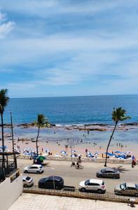 una playa con coches y gente en la arena y el océano en Belíssimo apartamento vista mar deslumbrante na Barra! Direto na praia e no circuito do Carnaval de Salvador., en Salvador