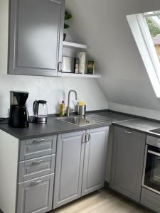 a kitchen with white cabinets and a sink at Ferienwohnung Eulennest in Drolshagen