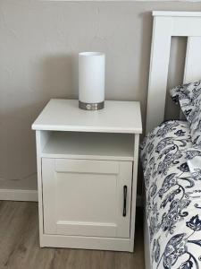 a white night stand next to a bed with a candle on it at Ferienwohnung Eulennest in Drolshagen