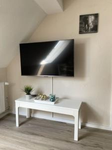 una mesa blanca en una habitación con TV en la pared en Ferienwohnung Eulennest en Drolshagen