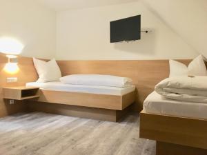a bedroom with two beds and a flat screen tv at Hotel Engel in Ulm