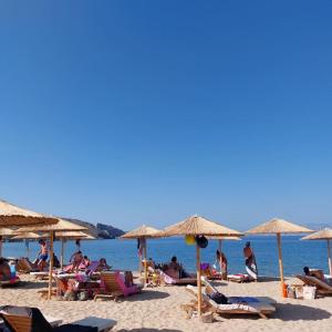 a group of people sitting on a beach with umbrellas at Psathi Beach in Psathi