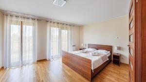 a bedroom with a bed with a wooden headboard and large windows at Apartamenty Sun & Snow Rozewie in Jastrzębia Góra