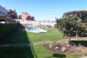 a garden with a swimming pool and a tree at Apartamento con piscina en Portosín in Portosin