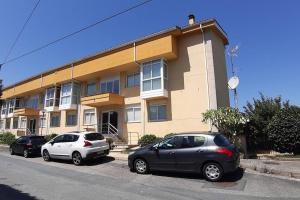 two cars parked in front of a building at Apartamento con piscina en Portosín in Portosin