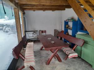 uma mesa e cadeiras num quarto com um fogão em Székelyföld ,Siklódi Kő Vendégház, Tornácosház em Bartoştana