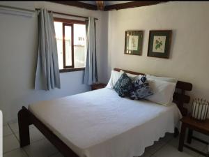 1 dormitorio con 1 cama blanca grande y ventana en Vila Bahia casa 3, en Porto Seguro