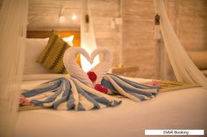 two towel swans making a heart on a bed at Dayung Villas By Reccoma in Nusa Lembongan