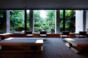 a room with tables and chairs and a large window at Yoshiike Ryokan in Hakone