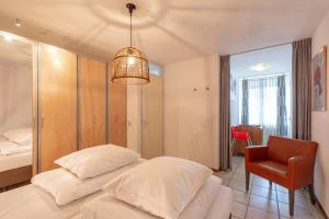 ein Schlafzimmer mit einem weißen Bett und einem Stuhl in der Unterkunft Wijde Blick appartement 210 Callantsoog in Callantsoog
