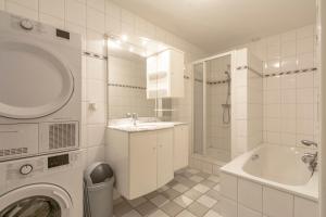 ein weißes Badezimmer mit einem Waschbecken und einer Waschmaschine in der Unterkunft Wijde Blick appartement 210 Callantsoog in Callantsoog