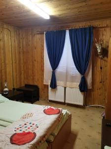 a bedroom with a bed and a window with blue curtains at Cabana Fantanita cu Brazi in Poiana Brasov