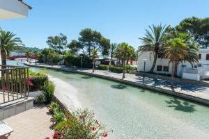 Blick auf einen Fluss mit Palmen und Gebäuden in der Unterkunft Gran Canal in Alcúdia