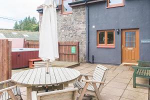 a table with an umbrella and chairs on a patio at Keepers Lodge with Hot Tub in Forgandenny