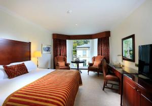 een hotelkamer met een bed, een bureau en stoelen bij Macdonald Norwood Hall Hotel in Aberdeen