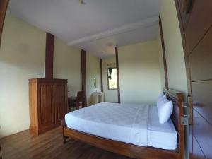 Schlafzimmer mit einem weißen Bett und einem Holzschrank in der Unterkunft Istana Petani in Lambangkuning
