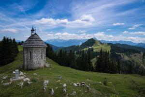 una torre de piedra en una colina con una montaña en Baita dei Colori, en Camporosso in Valcanale