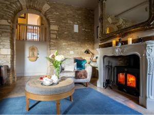 ein Wohnzimmer mit Kamin und einem Stuhl und einem Tisch in der Unterkunft Pineapple Spa Cottage in Stow on the Wold