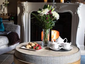 a coffee table with a vase of flowers and a plate of food at Pineapple Spa Cottage in Stow on the Wold