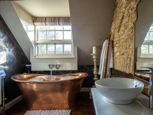 ein Badezimmer mit einer Kupferbadewanne und einem Waschbecken in der Unterkunft Pineapple Spa Cottage in Stow on the Wold