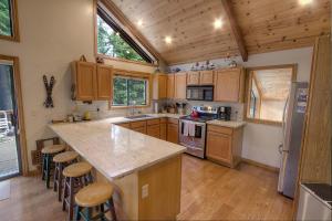 uma cozinha com armários de madeira e uma grande ilha com bancos de bar em Sunnyside Up cabin em Tahoe City