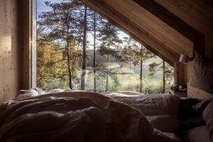 uma cama num quarto com uma grande janela em Hilltop Forest em Inkoo