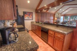 una cocina con armarios de madera y encimeras de granito en Brockway Beachside Bungalo home, en Kings Beach