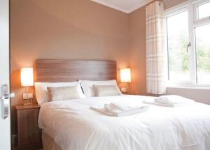 a bedroom with a large white bed with two towels on it at Warren Lodges in Little Baddow