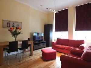 ein Wohnzimmer mit einem Sofa und einem Tisch mit einem TV in der Unterkunft Picardy Place Apartment in Edinburgh