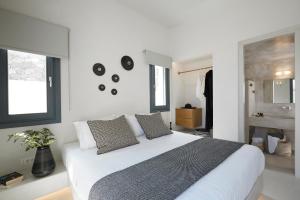 a white bedroom with a large bed and two windows at M&D Stories in Pirgos