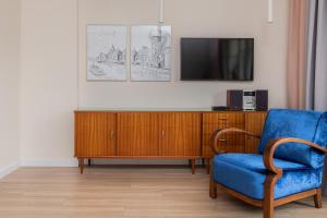 ein Wohnzimmer mit einem blauen Stuhl und einem TV in der Unterkunft Beach Apartment with Balcony Sopot by Renters in Sopot