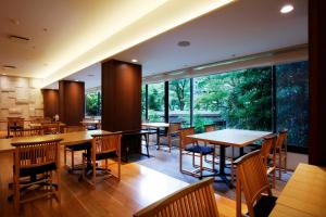 een restaurant met tafels en stoelen en grote ramen bij Yoshiike Ryokan in Hakone