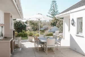 a patio with a table and chairs and an umbrella at Leisure Isle Seaside Cottage in Knysna