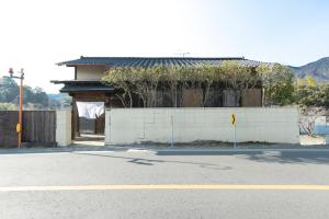a building with a white wall and a fence at The minpark in Dazaifu
