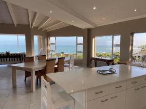 a kitchen with a table and chairs and windows at Loerie Nest in Port Alfred