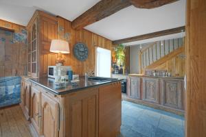 uma cozinha com armários de madeira, um lavatório e um relógio em Gîte de la Forêt em Theux