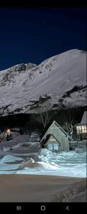 a snow covered mountain at night with a cabin at Koliba Činčila in Žabljak