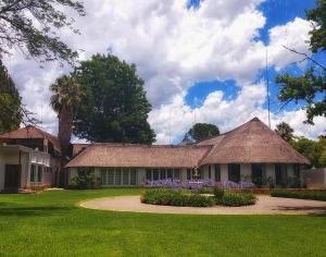 una casa con techo de paja y patio de césped en Clivia Lodge, en Vanderbijlpark