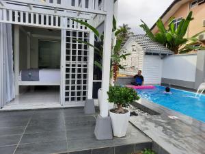 a man sitting next to a swimming pool next to a house at Beit Azzahra Private Pool Villa at Pantai Batu Hitam in Kuantan