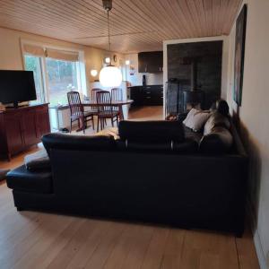 sala de estar con sofá negro y mesa en Vidunderligt hus i landlige omgivelser, en Spottrup