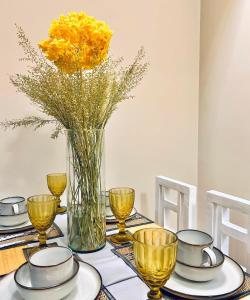 une table avec des assiettes et un vase avec des fleurs jaunes dans l'établissement LOVELY AND COZY -Executive 1BR in Uptown Parksuites Tower 1-BGC, à Manille