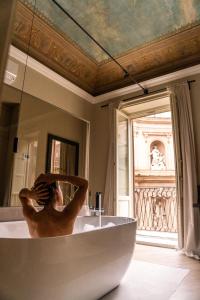 a woman in a bath tub in a bathroom with a mirror at InCanto in Palermo