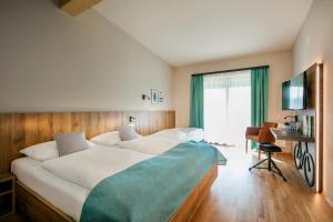 um quarto com uma grande cama branca e uma secretária em JUFA Hotel Erlaufsee em Mariazell