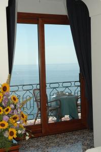 a room with a balcony with a table and flowers at Hotel Belvedere in Conca dei Marini
