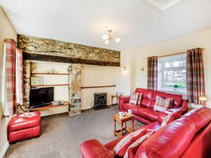 sala de estar con sofá de cuero rojo y chimenea en Hafod, en Llanengan