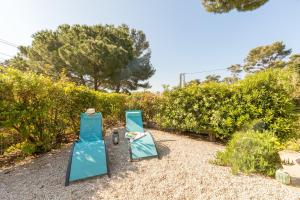 two chairs sitting on the sand next to some bushes at La Bastide, villa en duplex idéalement située à quelques pas de la mer in Hyères