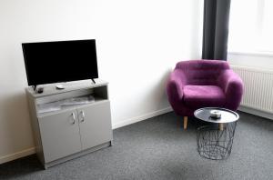 a living room with a purple chair and a tv at Luana Airport Apartments #6 in Otopeni